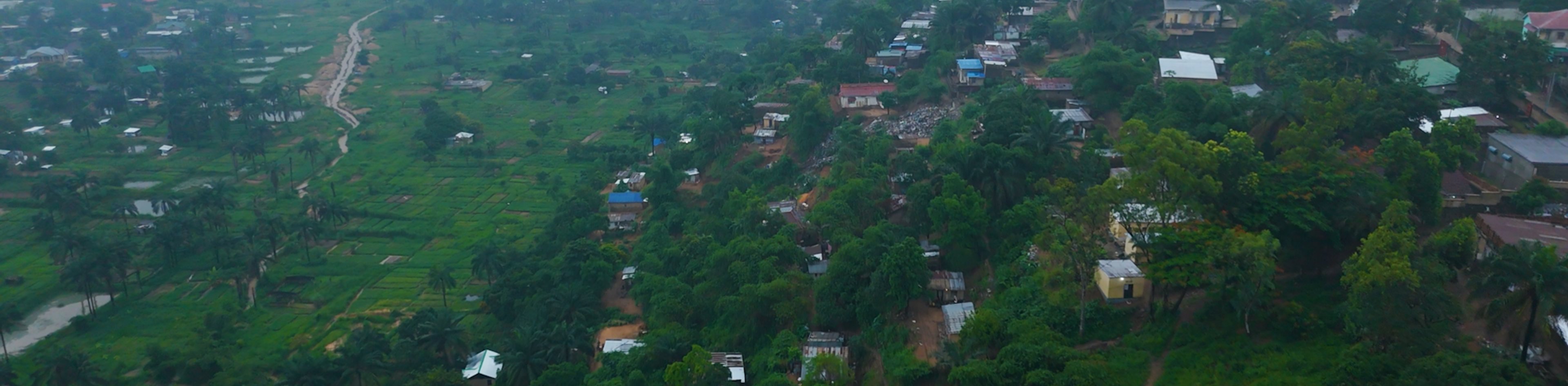 An aerial drone shot of a rural village with lush greenery.