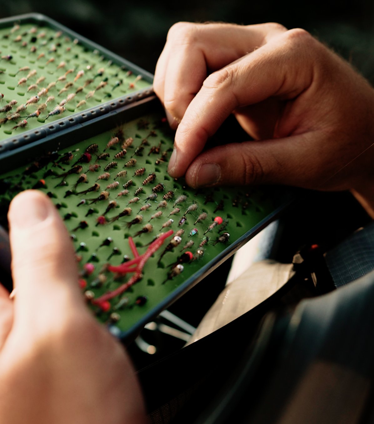 A fisherman picking a lure out of a tackle box.
